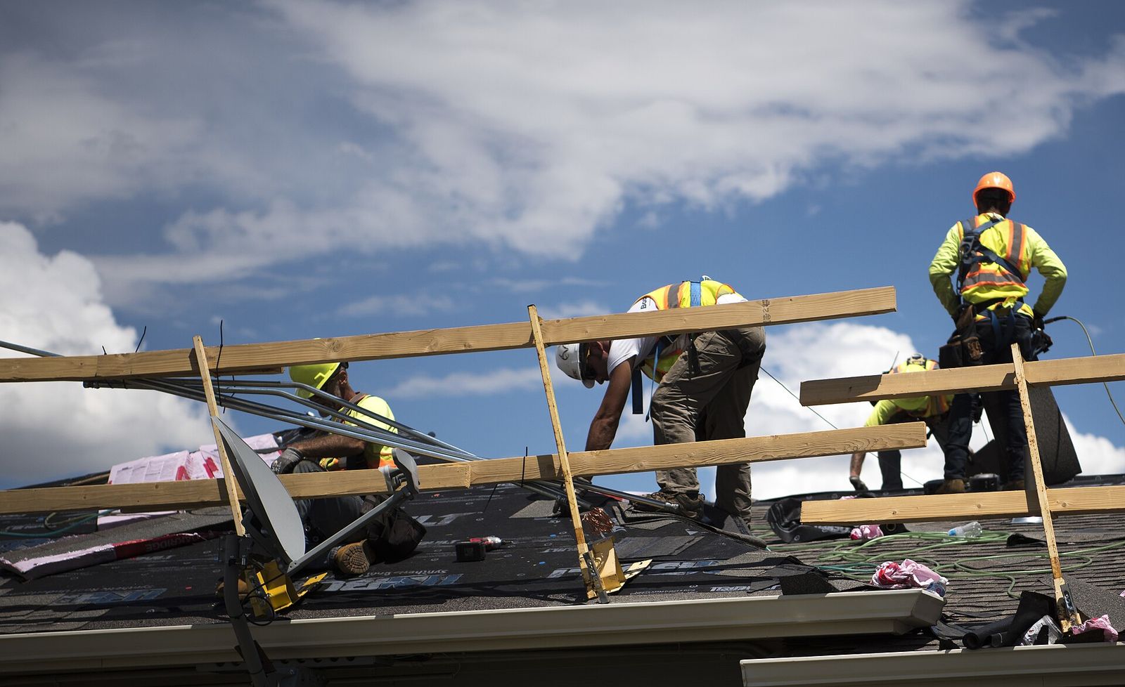 Northside Family Roofing crew setting decking on a roof under a clear sky