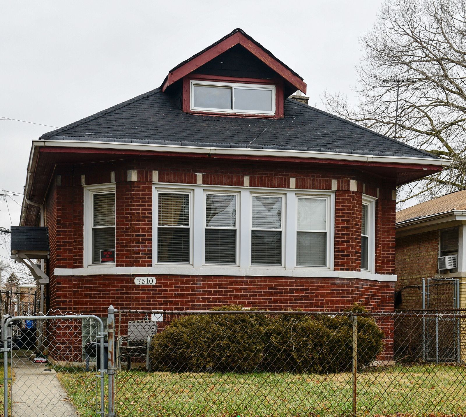 Brick Chicago bungalow with a new dark shingle roof and a red-trimmed dormer