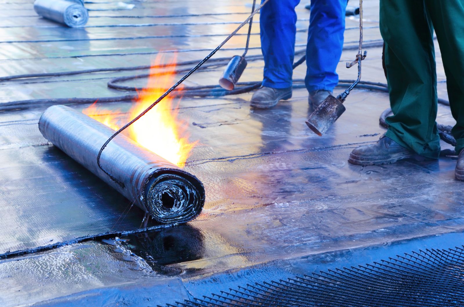 Crew torching modified bitumen on a flat commercial roof