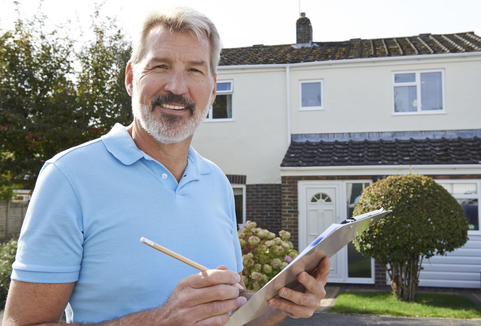 Frank, owner of Northside Family Roofing, in front of a finished house with the day's paperwork