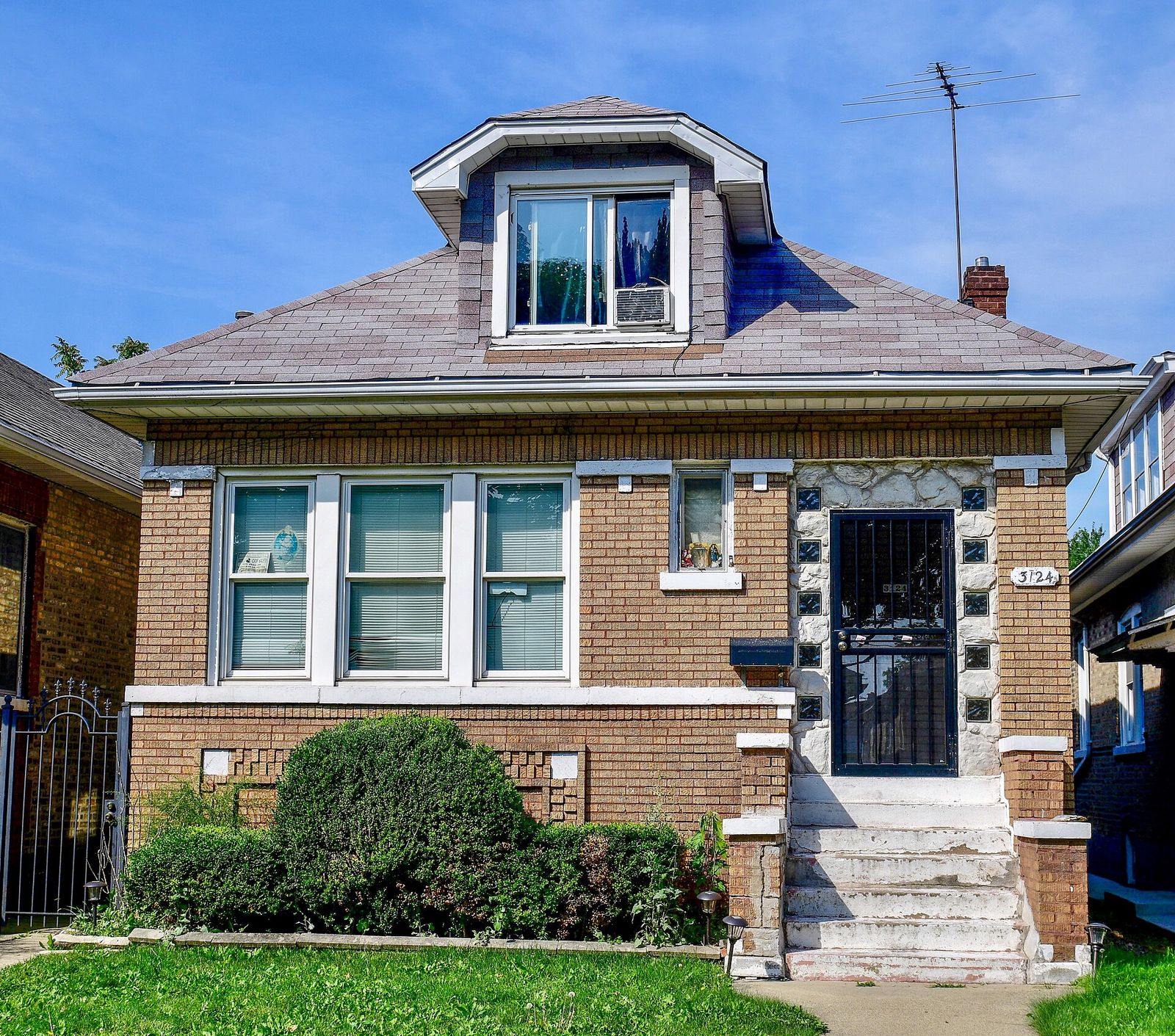 Brick Chicago bungalow with a new grey shingle roof and a hipped dormer