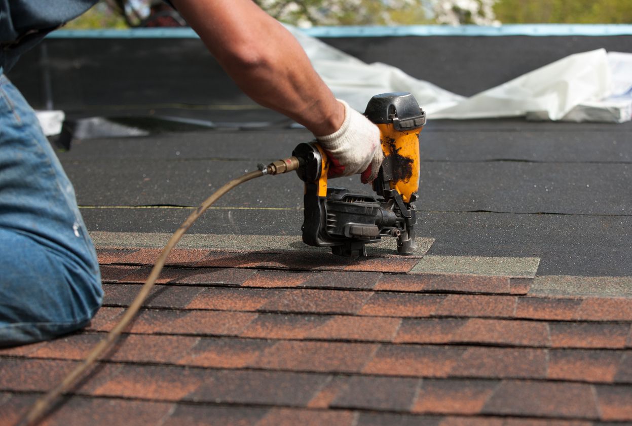 Roofer fastening architectural shingles with a nail gun